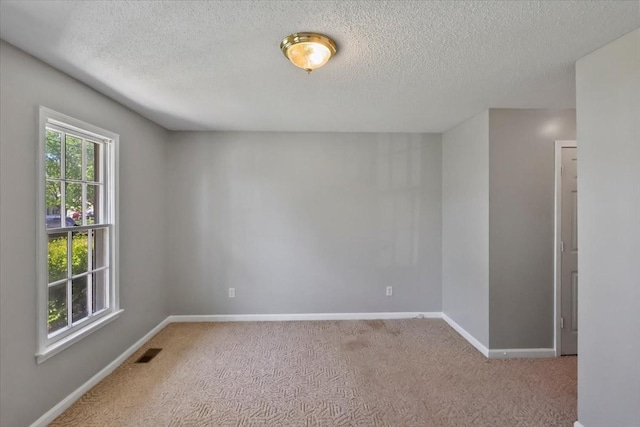 unfurnished room featuring a textured ceiling, baseboards, visible vents, and carpet floors
