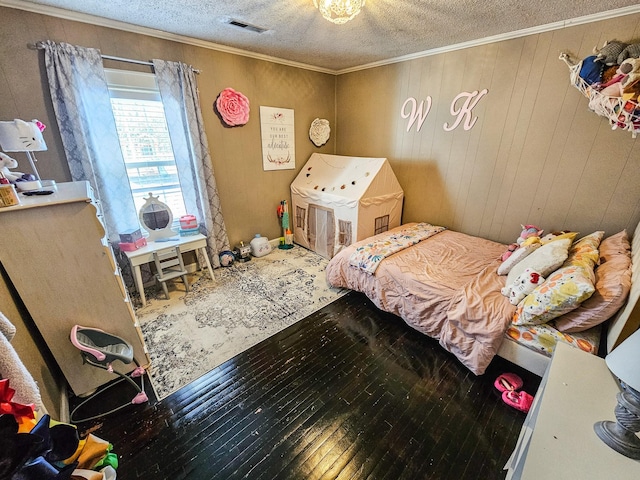 bedroom with hardwood / wood-style flooring, ornamental molding, a textured ceiling, and wooden walls