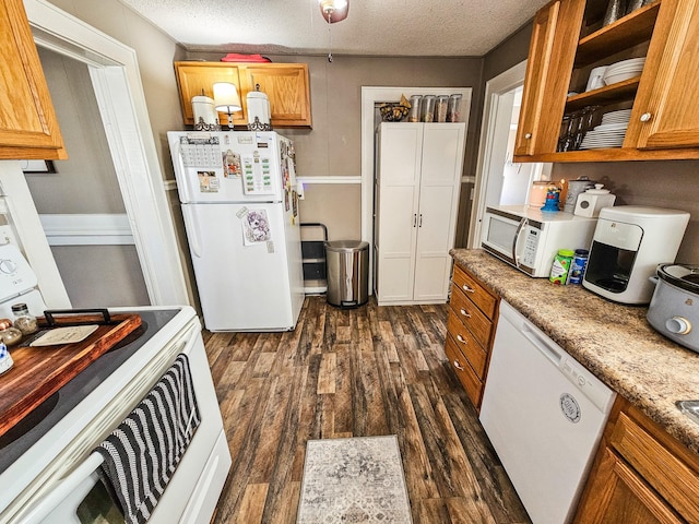 kitchen featuring light stone countertops, dark wood-type flooring, white appliances, and a textured ceiling