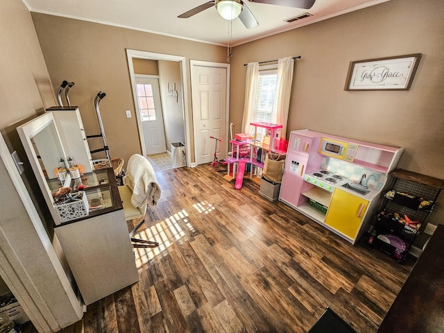 recreation room featuring ceiling fan, ornamental molding, and wood-type flooring