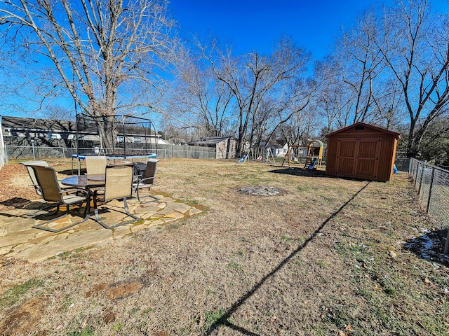 view of yard with a storage shed, a playground, and a trampoline