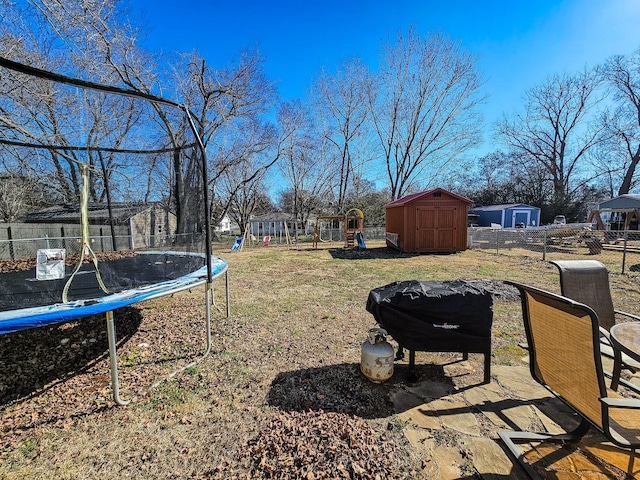 view of yard with a storage unit, a playground, and a trampoline