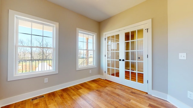 empty room with french doors and light wood-type flooring