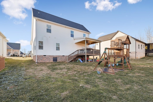 back of property with ceiling fan, a playground, and a lawn