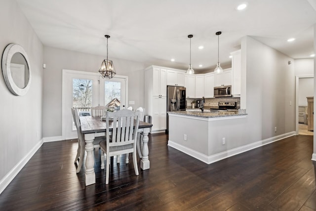 kitchen with dark hardwood / wood-style floors, pendant lighting, white cabinetry, light stone counters, and stainless steel appliances