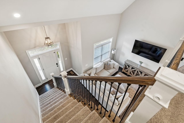 stairs featuring a notable chandelier, a high ceiling, hardwood / wood-style floors, and a wealth of natural light