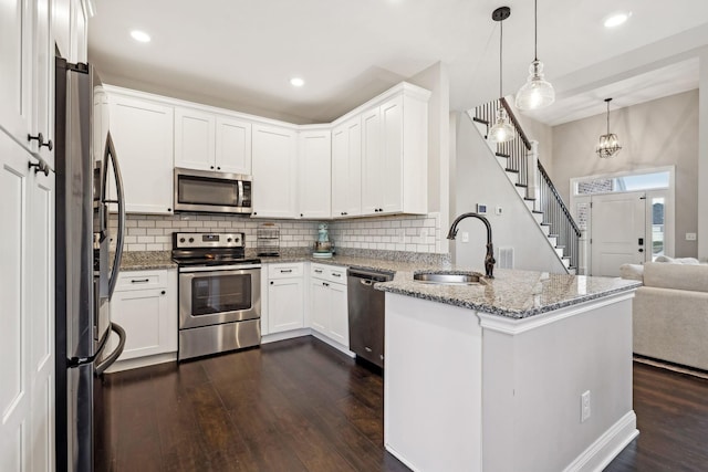 kitchen featuring sink, hanging light fixtures, stainless steel appliances, white cabinets, and kitchen peninsula