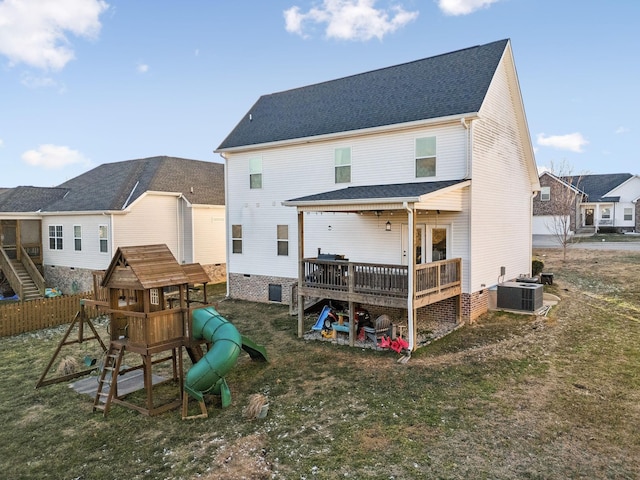 rear view of property with a yard, central AC, and a playground