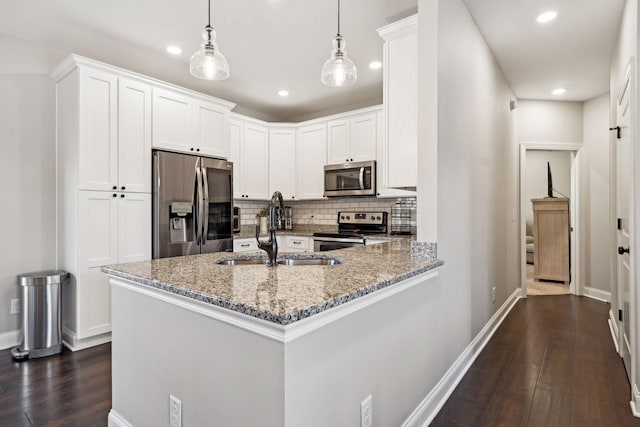 kitchen featuring sink, hanging light fixtures, kitchen peninsula, stainless steel appliances, and white cabinets