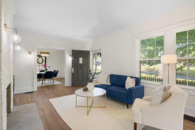 living room featuring dark hardwood / wood-style flooring, ornamental molding, and a stone fireplace