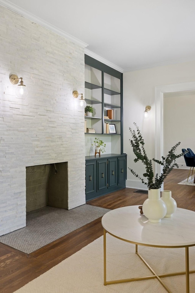 living room featuring built in features, a stone fireplace, ornamental molding, and dark hardwood / wood-style flooring