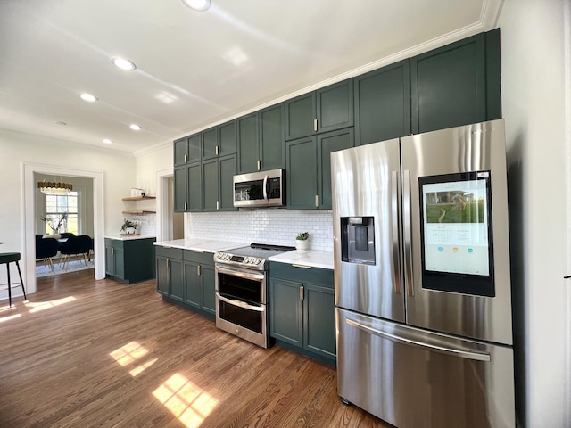 kitchen with green cabinets, decorative backsplash, ornamental molding, dark wood-type flooring, and stainless steel appliances