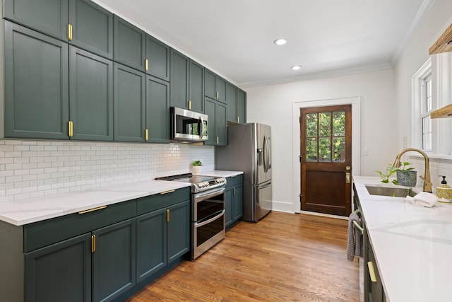 kitchen featuring decorative backsplash, sink, appliances with stainless steel finishes, and green cabinetry