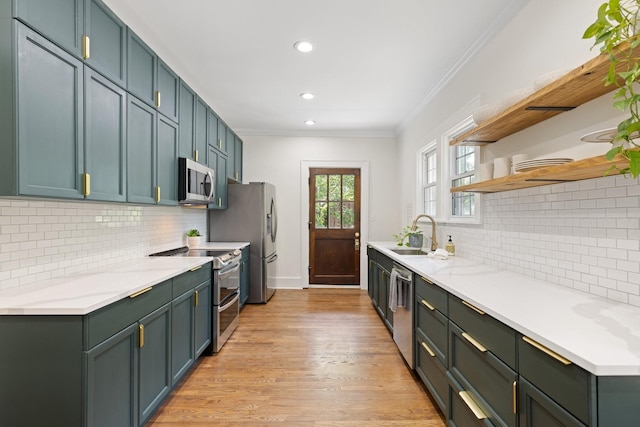 kitchen with light stone countertops, appliances with stainless steel finishes, light hardwood / wood-style floors, sink, and crown molding