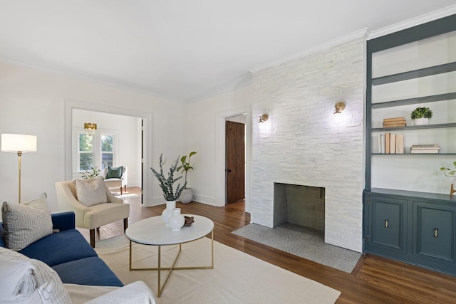 living room with crown molding, built in shelves, dark hardwood / wood-style floors, and a stone fireplace