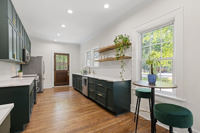 kitchen with stainless steel appliances, tasteful backsplash, light hardwood / wood-style floors, sink, and crown molding