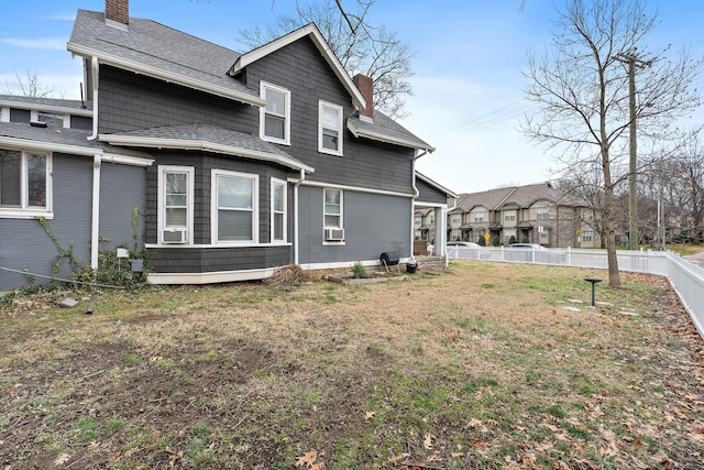 rear view of property with cooling unit and a yard