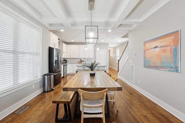 dining space with dark hardwood / wood-style floors, beam ceiling, and coffered ceiling