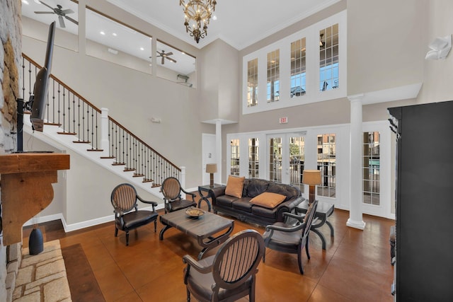 living room featuring a towering ceiling, ornate columns, crown molding, french doors, and ceiling fan