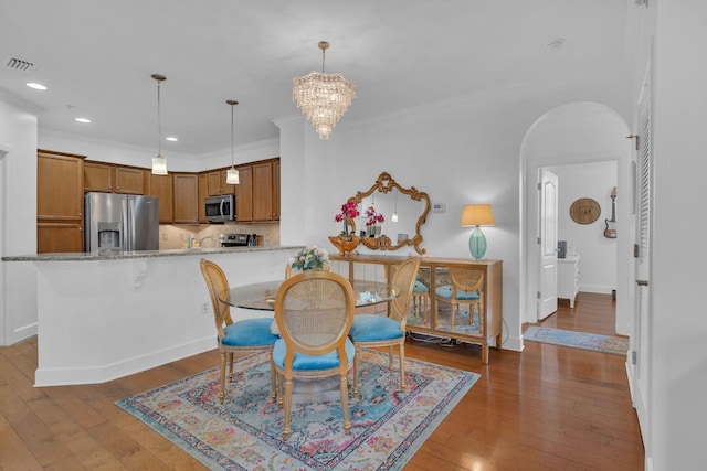 dining room featuring crown molding, dark wood-type flooring, and an inviting chandelier