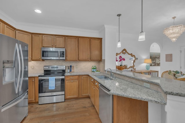 kitchen featuring appliances with stainless steel finishes, sink, kitchen peninsula, pendant lighting, and light stone counters