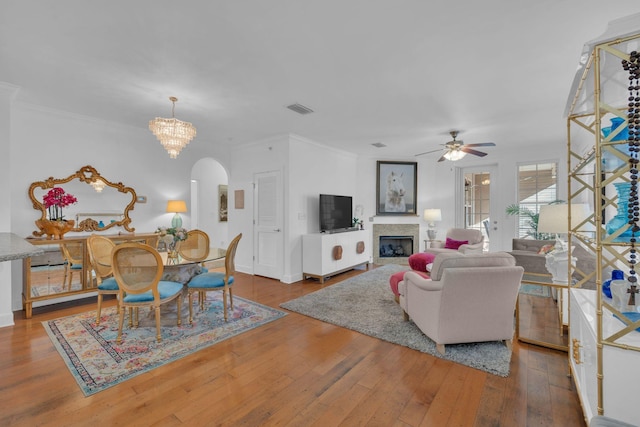 living room featuring ornamental molding, ceiling fan with notable chandelier, and hardwood / wood-style floors