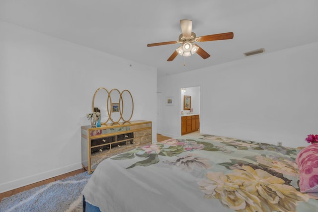 bedroom with light wood-type flooring, ceiling fan, and connected bathroom