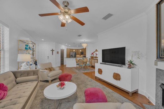 living room featuring a premium fireplace, ceiling fan, light hardwood / wood-style flooring, and ornamental molding