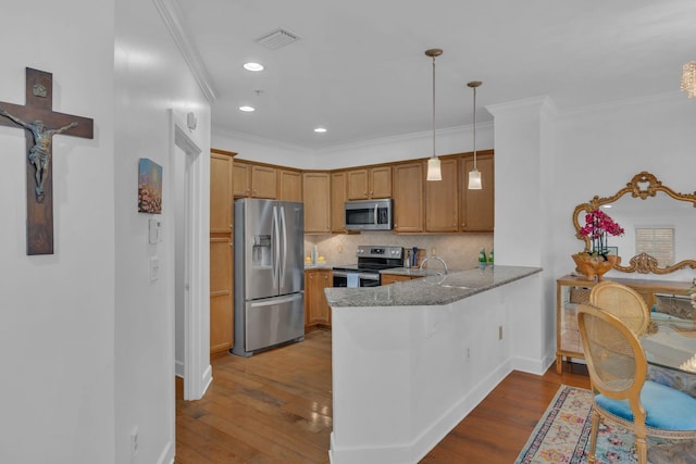 kitchen with kitchen peninsula, hanging light fixtures, appliances with stainless steel finishes, tasteful backsplash, and light stone countertops