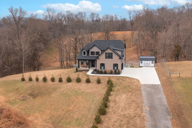 view of front facade with covered porch, a front lawn, and a storage shed