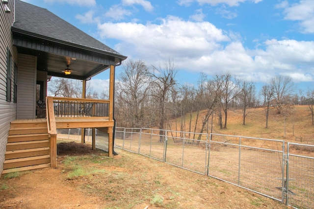 view of yard featuring ceiling fan, a wooden deck, and a rural view