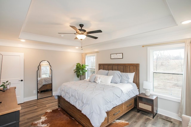 bedroom with ceiling fan, a raised ceiling, and dark hardwood / wood-style flooring