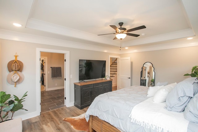 bedroom featuring hardwood / wood-style flooring, ceiling fan, and a raised ceiling