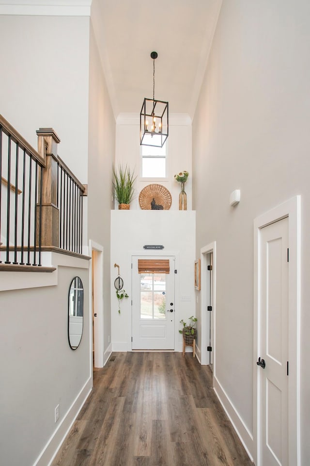 entrance foyer with a chandelier, a high ceiling, crown molding, and dark hardwood / wood-style floors