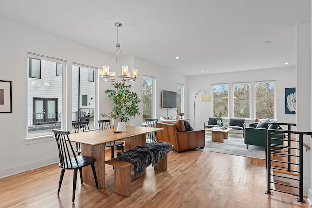 dining space featuring light hardwood / wood-style flooring, a notable chandelier, and a wealth of natural light