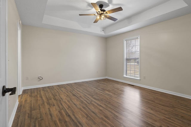 spare room featuring ceiling fan, dark hardwood / wood-style flooring, and a tray ceiling