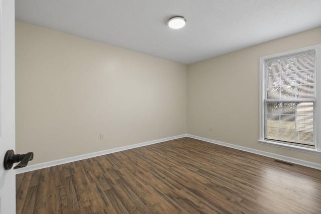 spare room with dark wood-type flooring and plenty of natural light