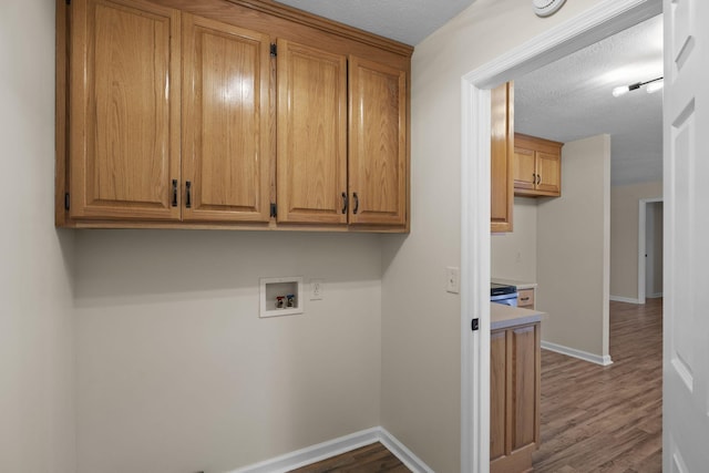 laundry area with hookup for a washing machine, cabinets, a textured ceiling, and dark hardwood / wood-style flooring