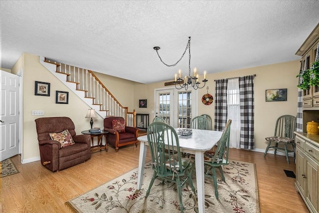 dining room featuring a textured ceiling, light hardwood / wood-style flooring, and an inviting chandelier