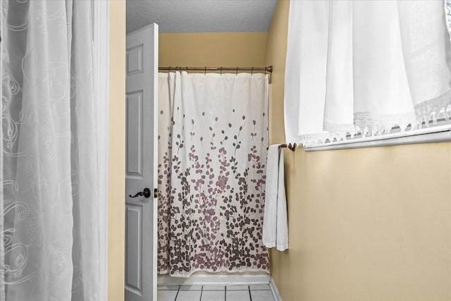 bathroom with a textured ceiling and tile patterned floors