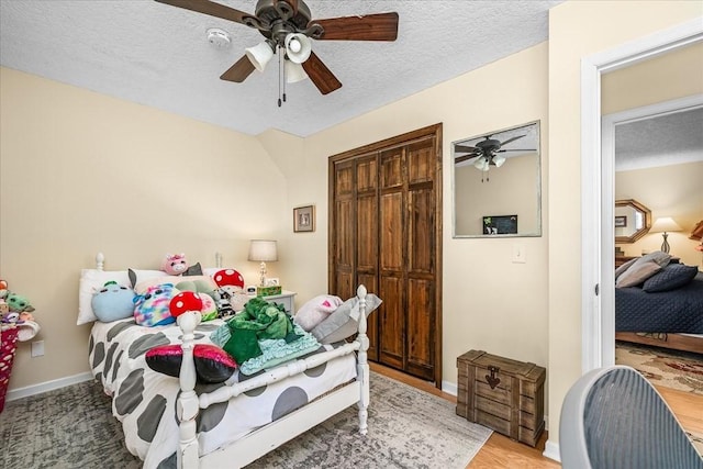 bedroom featuring ceiling fan, a textured ceiling, hardwood / wood-style flooring, and a closet