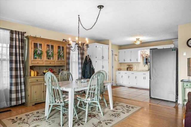 dining room featuring sink, light hardwood / wood-style floors, and a notable chandelier