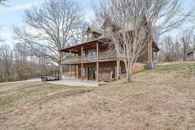 back of property with a deck, a patio area, a lawn, and central AC