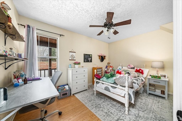 bedroom with ceiling fan, hardwood / wood-style floors, and a textured ceiling