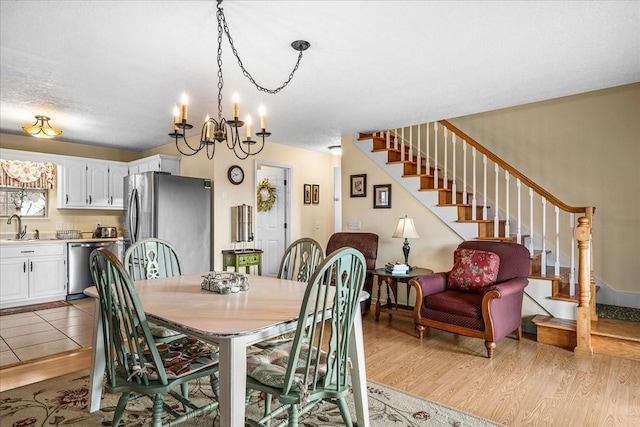 dining area featuring sink, a notable chandelier, and light wood-type flooring