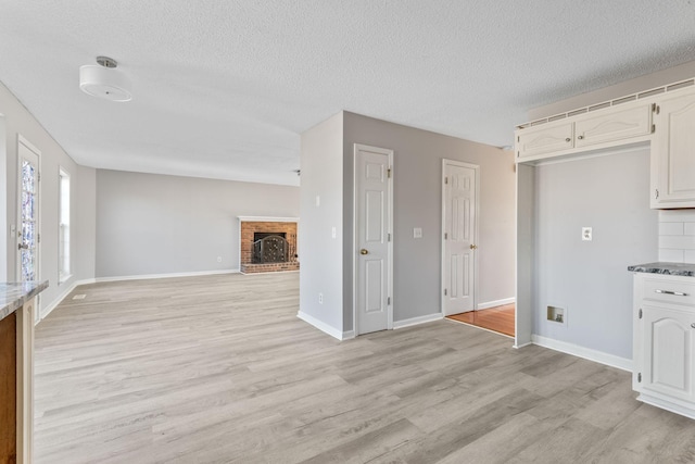 kitchen with a fireplace, light hardwood / wood-style floors, white cabinetry, and a textured ceiling