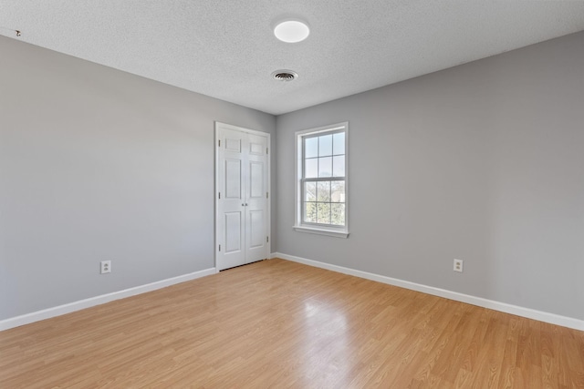 empty room featuring light hardwood / wood-style flooring and a textured ceiling