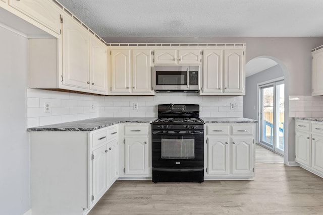 kitchen featuring a textured ceiling, white cabinetry, light hardwood / wood-style flooring, black range with gas stovetop, and backsplash