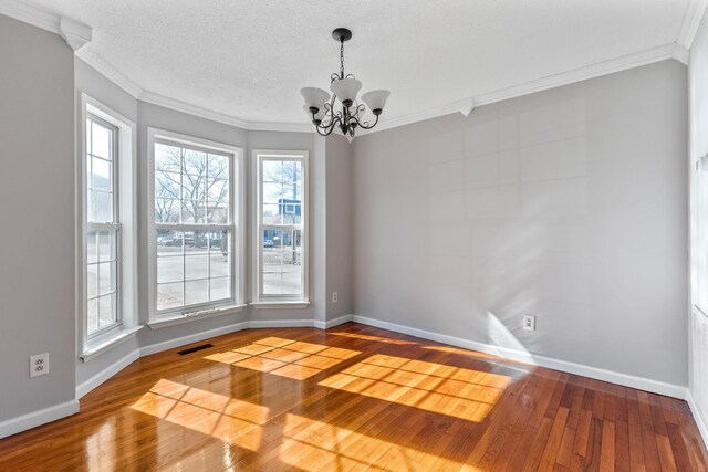 spare room featuring ornamental molding, an inviting chandelier, a textured ceiling, and wood-type flooring