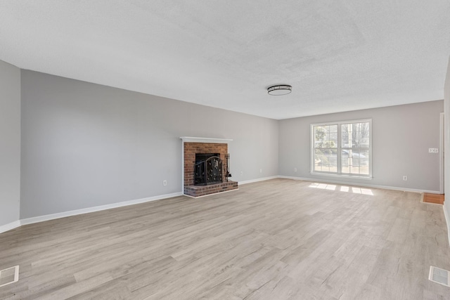 unfurnished living room with light hardwood / wood-style floors, a textured ceiling, and a fireplace